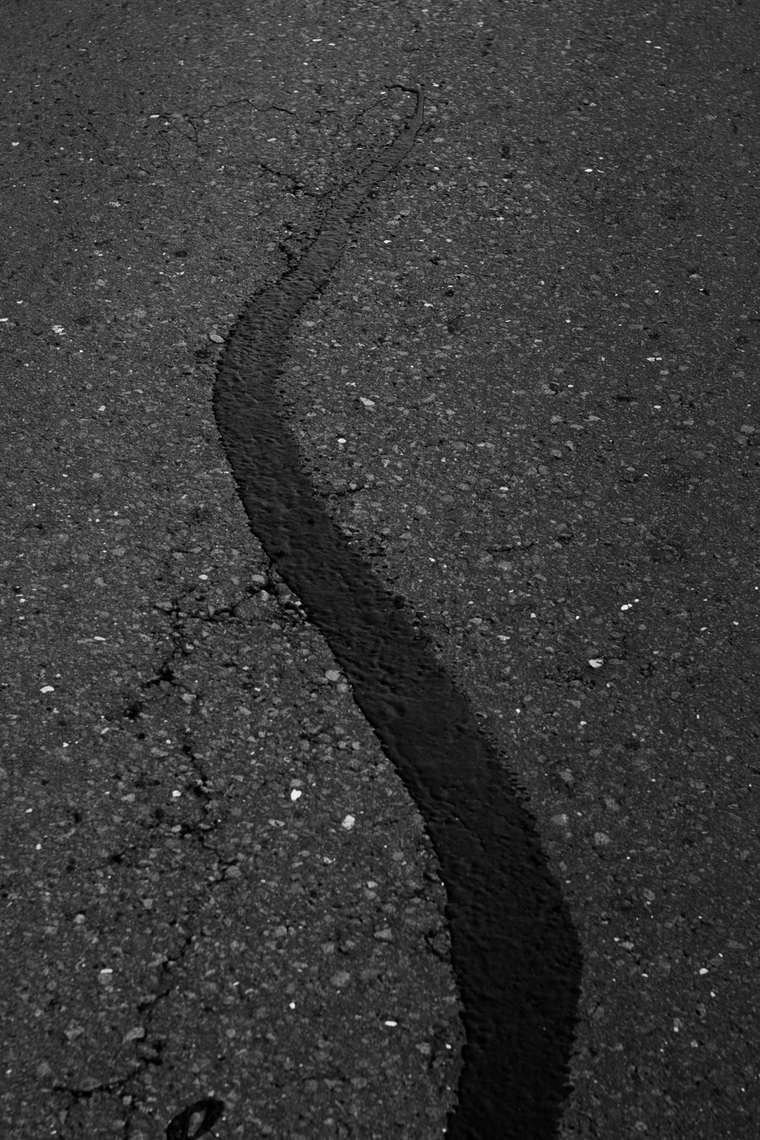 A long crack in asphalt filled with black sealant